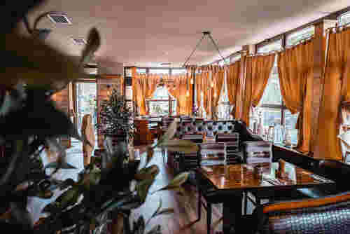 Das Bild zeigt ein stilvoll eingerichtetes Restaurant mit großen Fenstern, eleganten Vorhängen und gemütlichen Sitzbereichen. Das Bild zeigt ein stilvoll eingerichtetes Restaurant mit großen Fenstern, eleganten Vorhängen und gemütlichen Sitzbereichen.